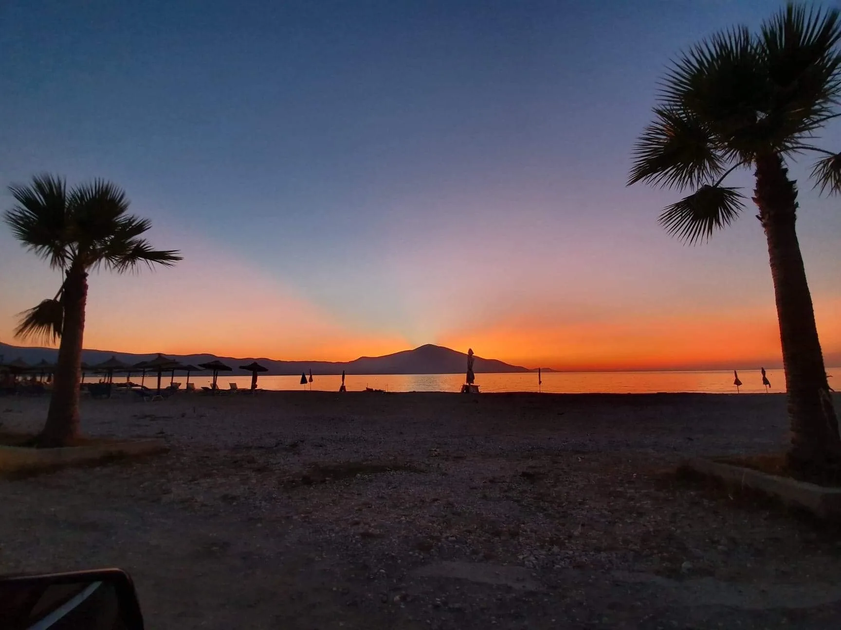 Sun loungers and umbrellas on Orikum seafront at sunset