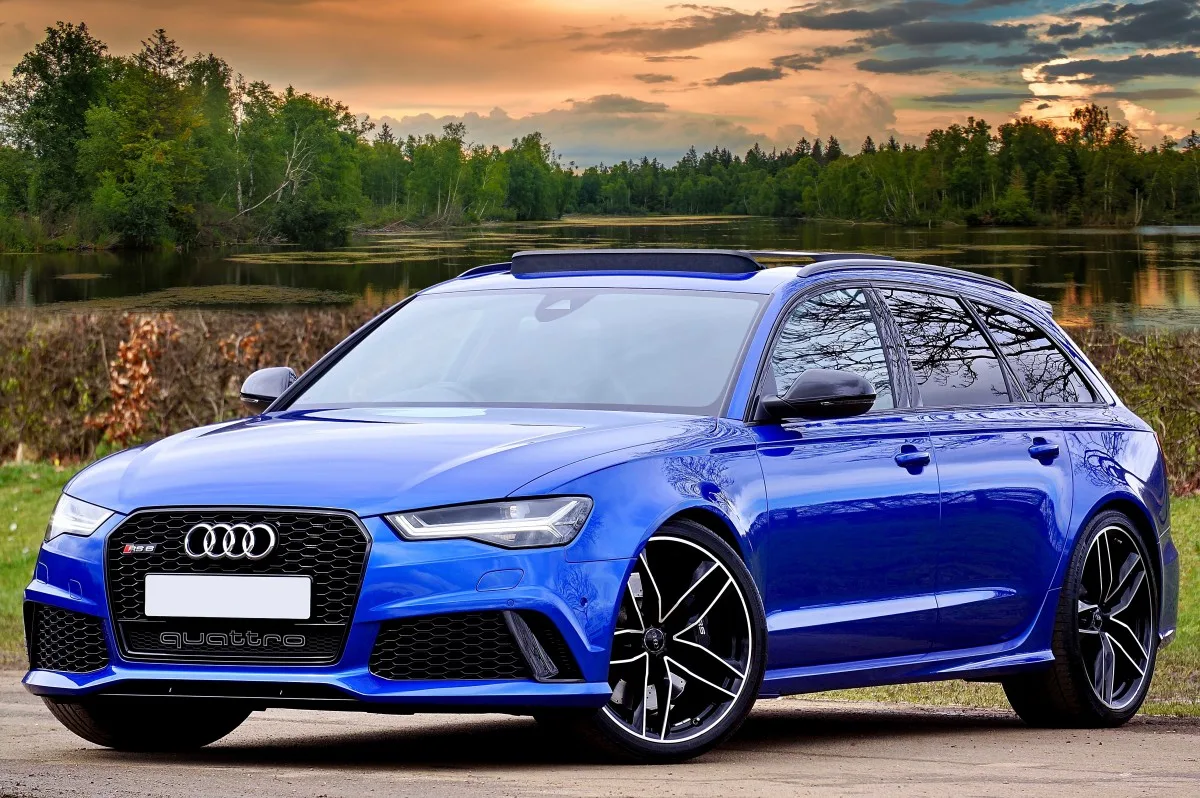 Blue Audi RS6 Avant parked on a road with a scenic background.
